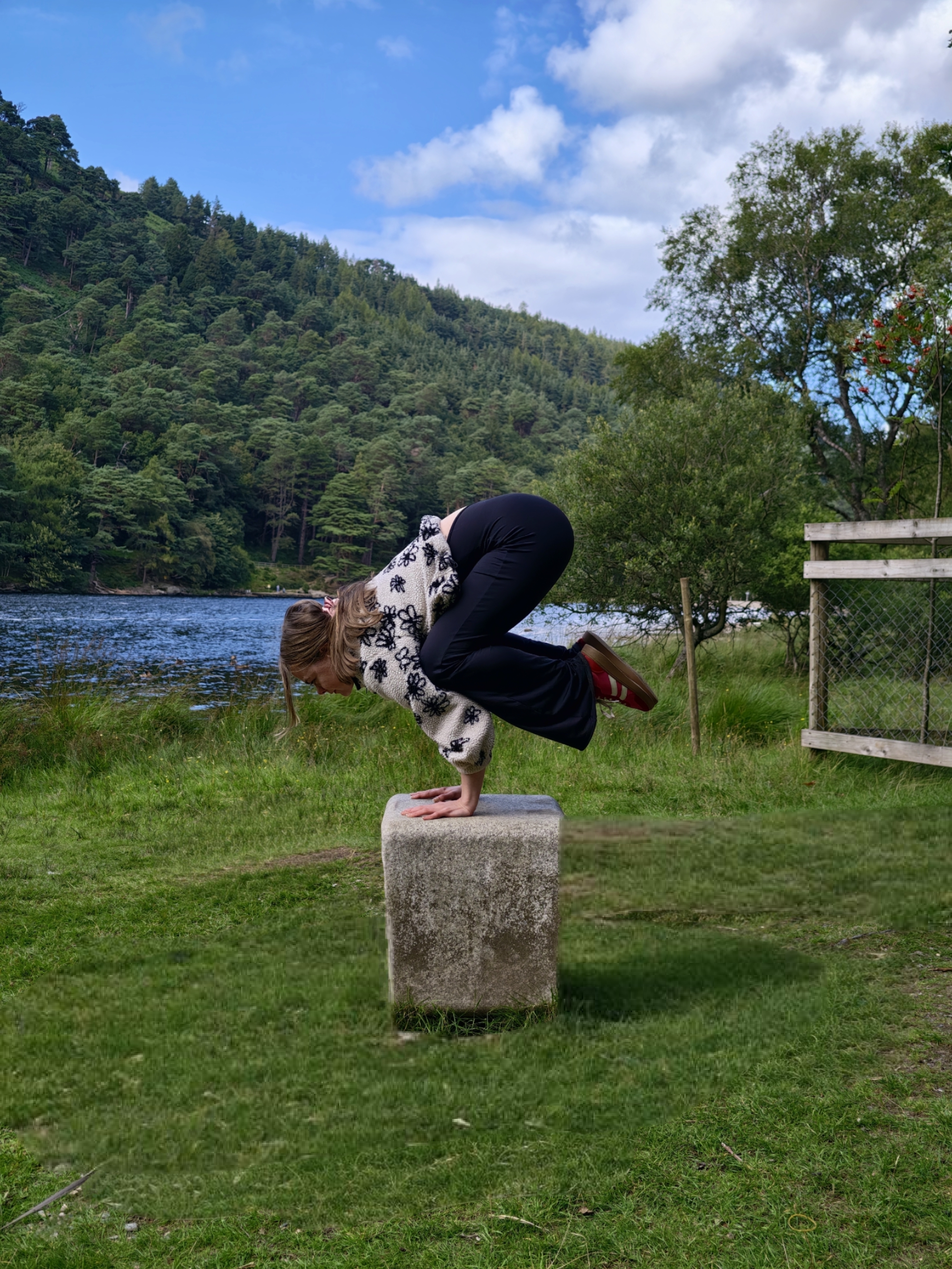 Person balancing on stone near lake